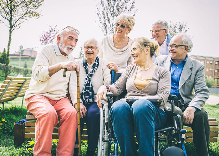 Photo featuring a group of elderly people sitting outside.