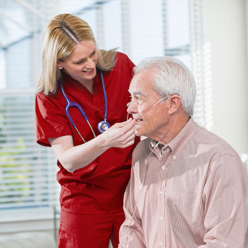 female nurse helping older male with oxygen tube