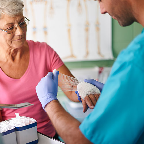 male medical professional helping an older woman with a wound care wrap